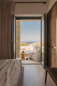 a bedroom with a bed and a large window at Bard De Sol in Mikonos