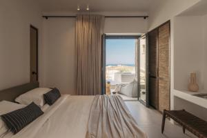 una camera con un grande letto e una grande finestra di Bard De Sol a Mykonos Città
