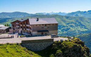 a large building on a hill with mountains in the background at Lagrange Vacances Les Chalets de l'Adet in Saint-Lary-Soulan