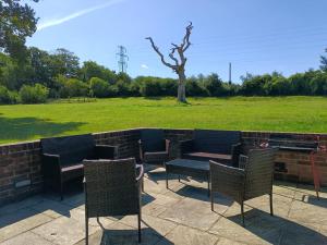 eine Terrasse mit Stühlen, einem Grill und einem Feld in der Unterkunft Iffin Farmhouse in Canterbury