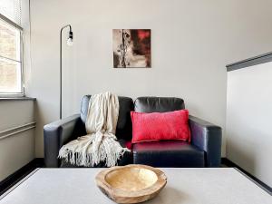 a living room with a black leather couch and red pillows at Sleepover Luxe Downtown Springfield Apartments in Springfield