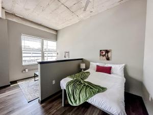 a bedroom with a bed with a green blanket on it at Sleepover Luxe Downtown Springfield Apartments in Springfield