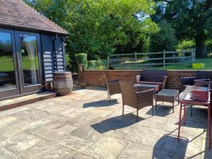 a patio with chairs and tables and a building at Iffin Farmhouse in Canterbury