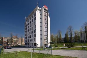 a white building with a red sign on top of it at Penzion a ubytovna Oáza in Otrokovice