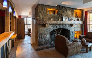 - un salon avec une cheminée en pierre dans l'établissement Lagrange Vacances Les Chalets de l'Adet, à Saint-Lary-Soulan