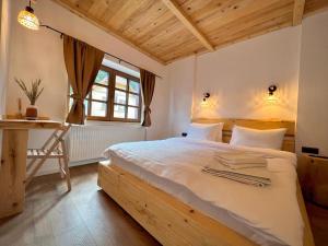 a bedroom with a bed with a desk and a window at Victoria Gasthaus Rasnov - charming vacation house in Rasnov in Râşnov
