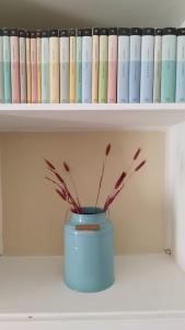 a blue vase sitting on a shelf with books at Villa tra gli ulivi in San Pietro in Bevagna