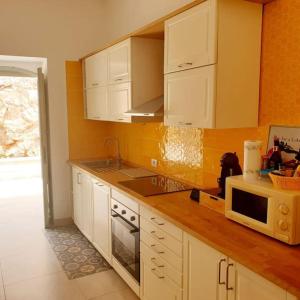 eine Küche mit weißen Schränken, einer Spüle und einer Mikrowelle in der Unterkunft Rifugio di Sibir in Selva di Fasano