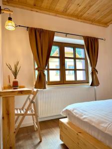 a bedroom with a bed and a desk and a window at Victoria Gasthaus Rasnov - charming vacation house in Rasnov in Râşnov