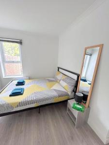 ein Schlafzimmer mit einem großen Bett und einem Spiegel in der Unterkunft New Florence Rooms in Mitcham