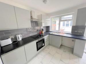 a kitchen with white cabinets and black counter tops at New Florence Rooms in Mitcham