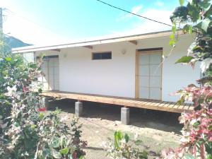 una casa blanca con un banco delante en TEMAEVA LODGE, en Nuku Hiva