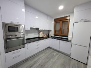 Una cocina con gabinetes blancos y electrodomésticos de acero inoxidable. en Casa albalunasss, en Salamanca
