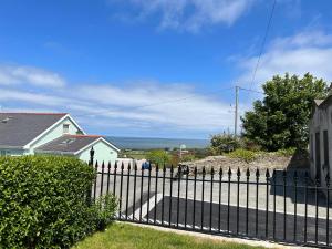 een zwart hek met de oceaan op de achtergrond bij Converted Welsh Sunday School with Sea View & Garden on Anglesey - Dog Friendly in Amlwch