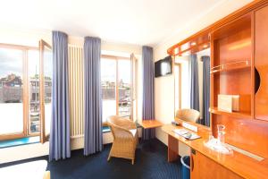 una camera d'albergo con scrivania e finestra di Hotel Kontorhaus Stralsund a Stralsund