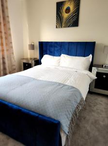 1 cama grande con cabecero azul en un dormitorio en Spacious detached 3 bed,2 bath house with private garden&parking located near city centre, en Sheffield