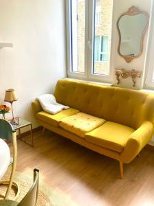 a yellow couch in a room with a window at foodiejive appartement 2 in Antwerp