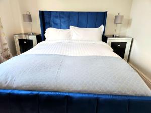 duże łóżko z niebieskim zagłówkiem w sypialni w obiekcie Beeches House - Stylish Detached house with private garden located near city centre w Sheffield