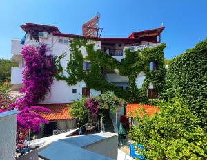 a building covered in ivy with purple flowers at Haus Niko Apartments and Suites in Nea Potidaea