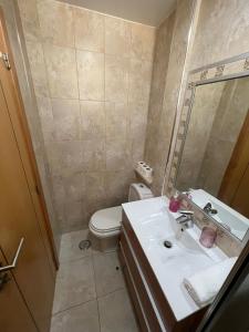 W łazience znajduje się umywalka, toaleta i lustro. w obiekcie Apartamento Familia Silva w mieście Nazaré