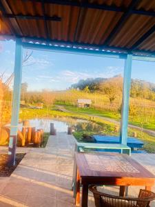 Un porche con una mesa y vistas a un estanque. en Cabana nas Nuvens, en São Marcos