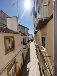 an alley between two buildings with the sun in the sky at Apartamento Familia Silva in Nazaré