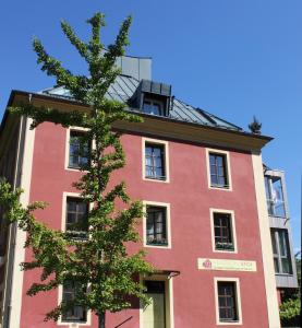 ein rotes Gebäude mit einem Baum davor in der Unterkunft Pension Stoi budget guesthouse in Innsbruck