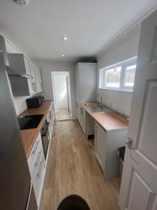 uma cozinha com armários brancos e pisos em madeira em Seaside Paradise em Lowestoft