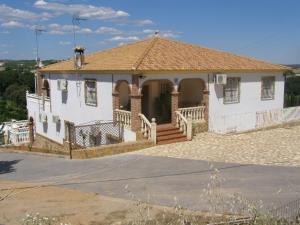 une grande maison blanche avec un porche et une allée dans l'établissement Casa Rural el Pinar en Posadas Córdoba, à Posadas