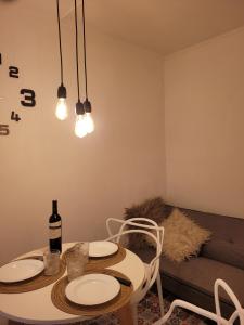 una mesa de comedor con 2 platos blancos y una botella de vino en Departamentos Ines 2 en Junín