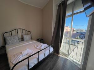 ein Schlafzimmer mit einem Bett und einem großen Fenster in der Unterkunft Suites DP Setúbal in Setúbal