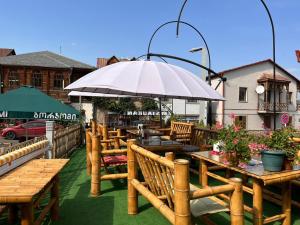 eine Terrasse mit Holztischen und -stühlen mit Sonnenschirm in der Unterkunft Old Rabati in Achalziche