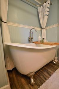 a white bath tub sitting on top of a wooden floor at Home On The Hill - Near EVERYTHING Charleston in Charleston