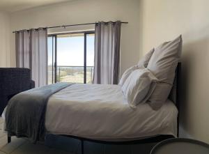 een slaapkamer met een bed met kussens en een raam bij H&H Self-catering in Windhoek
