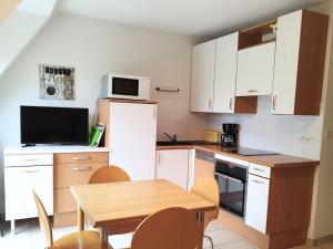 a kitchen with white cabinets and a table and a microwave at Plage à 300m - Appartement 4 personnes - Parking privé in Pornichet