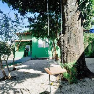 a swing hanging from a tree in front of a house at Casa central aconchegante in Alto Paraíso de Goiás