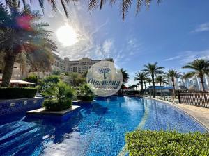 a swimming pool at a resort with palm trees at Harmony Vacation Homes - South Residence in Dubai