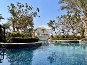 a swimming pool at a resort with palm trees at Harmony Vacation Homes - South Residence in Dubai
