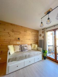 Un dormitorio con una pared de madera y una cama en Chalereux studio a la montagne, en Auron