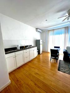 a kitchen with white cabinets and a wooden floor at Dushi Apartments in Willemstad