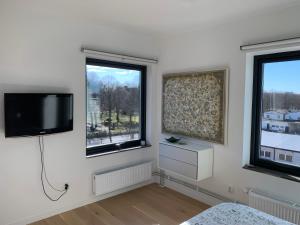 a bedroom with two windows and a flat screen tv at Lottas Beautiful Penthouse Apartment in Malmö