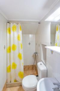 a bathroom with a toilet and a shower curtain with yellow flowers at Villa Vojka Naile in Pigi