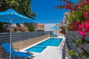 a swimming pool with a blue umbrella and chairs and flowers at Villa Vojka Naile in Pigi