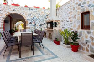 a patio with a table and chairs and a stone wall at Villa Vojka Naile in Pigi