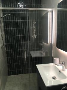 uma casa de banho em azulejos pretos com um lavatório e um chuveiro em The Plain View em Boyle