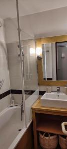 uma casa de banho com um lavatório, uma banheira e um espelho. em La Perle de l'Océan em Arzon