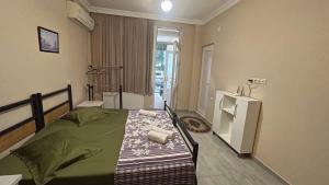 een slaapkamer met een groen bed en een raam bij Guest House Kldiashvili in Batoemi