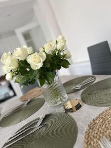 a vase filled with white roses sitting on a table at OurGreystones - Pet friendly home from home stay. in Valley