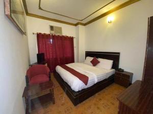 a bedroom with a bed and a red chair at Bab Al Bahrain Hotel in Manama