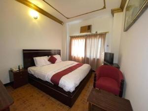 a bedroom with a bed and a red chair at Bab Al Bahrain Hotel in Manama